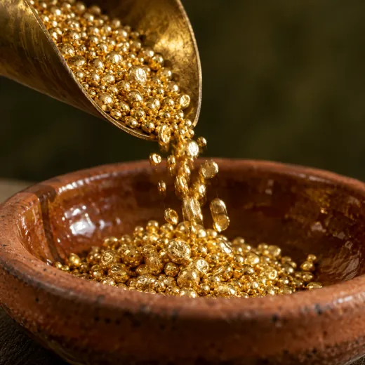 Recycled gold grains pouring from a brass scoop